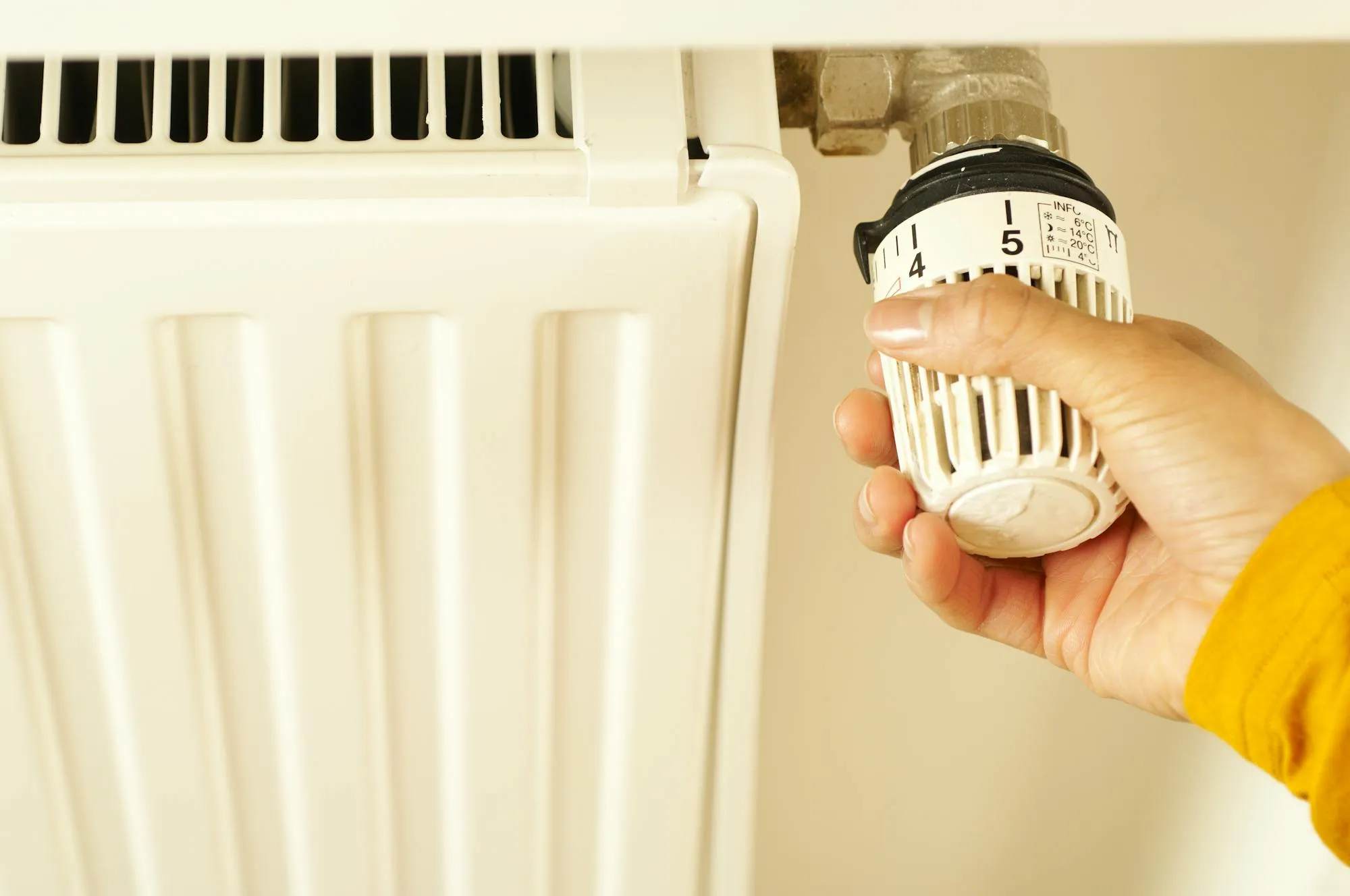 Hand adjusting a radiator thermostatic valve during a heating service